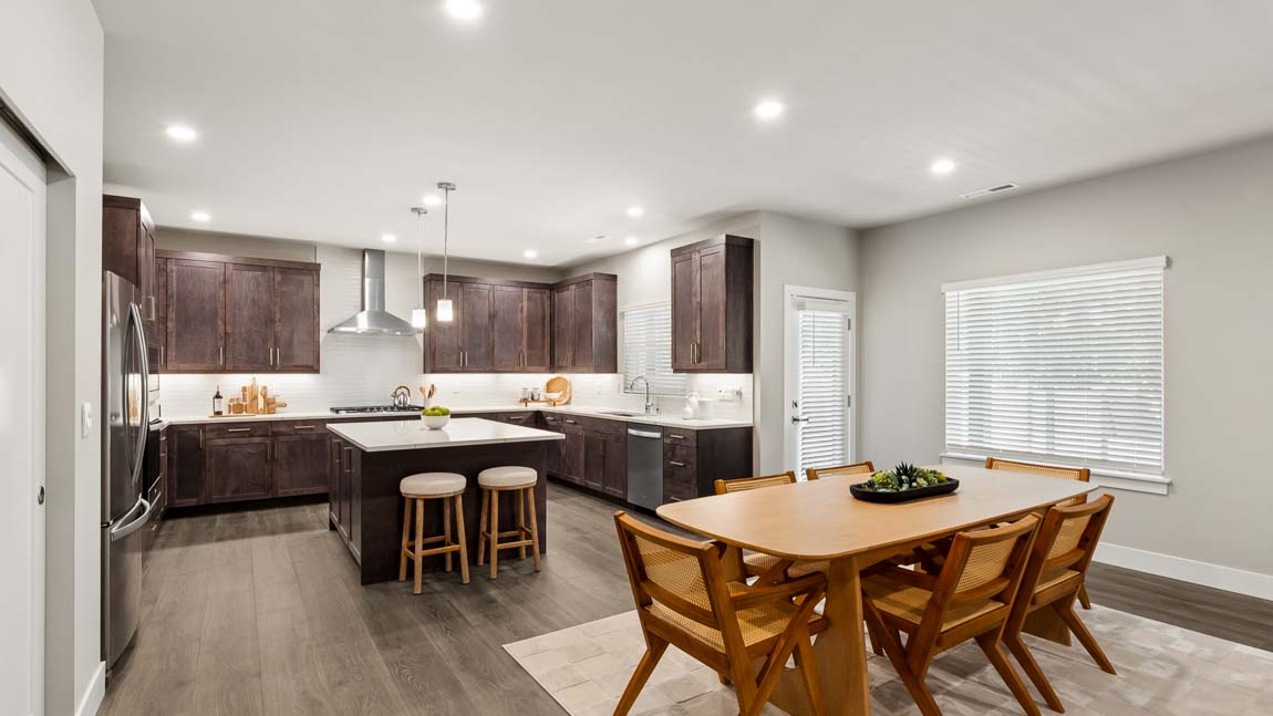 Open dining room connected to gourmet kitchen with center island, pendant lights, and modern finishes.