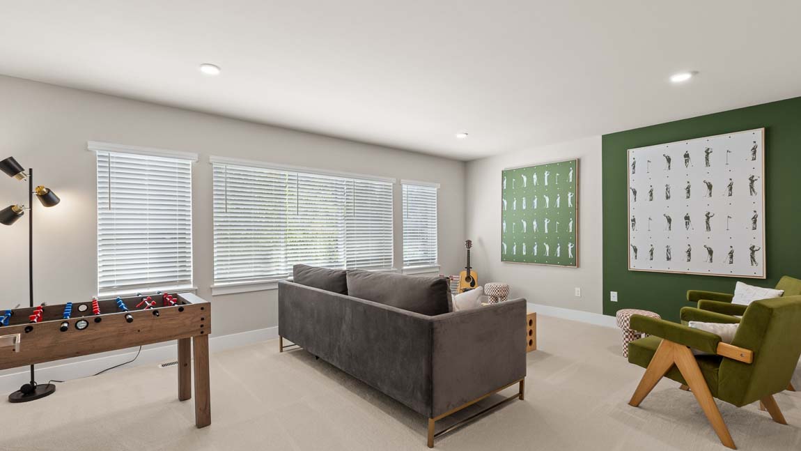 Recreation room with foosball table, sofa, accent chairs, guitar, and decorative green feature wall.