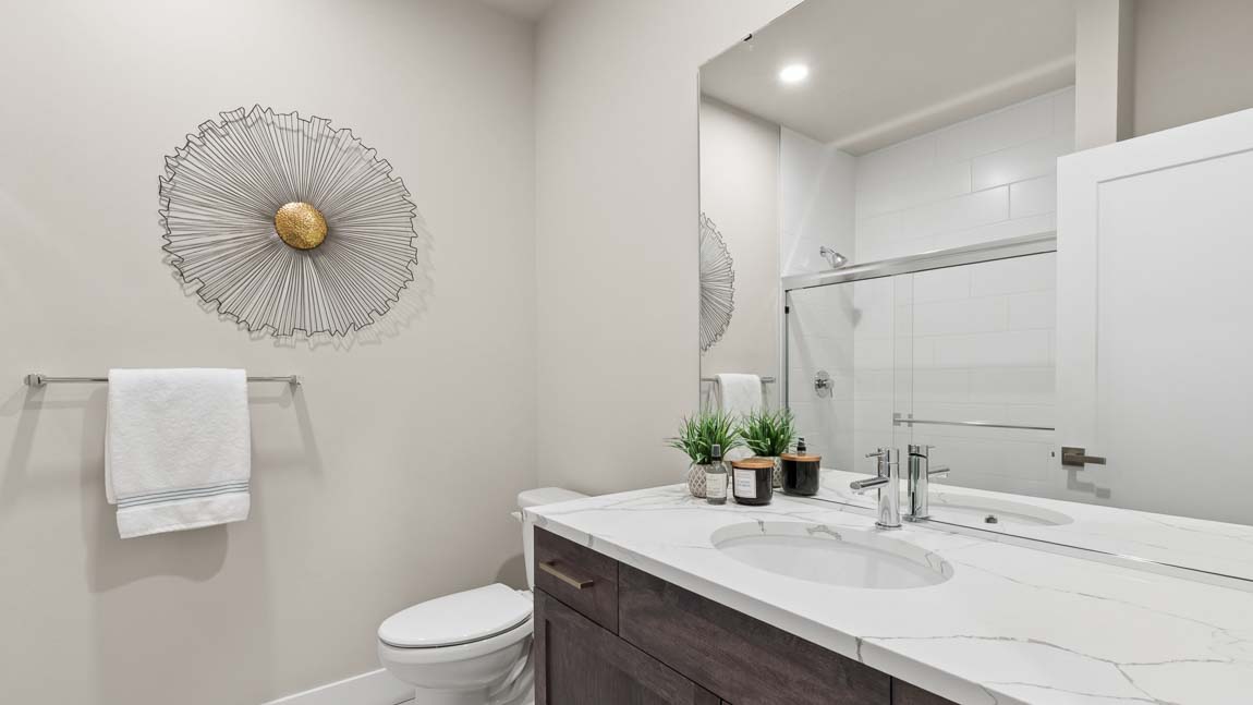 Bathroom with single-sink vanity, large mirror, quartz countertop, toilet, and glass-enclosed shower.