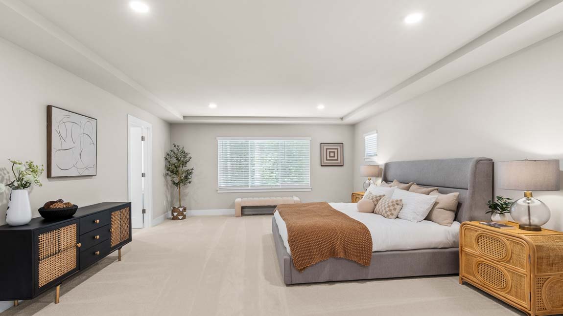 Spacious primary suite featuring oversized bedroom, decorative dresser, and private bathroom access.