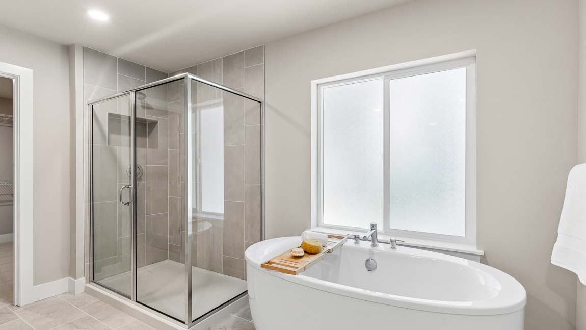 Spa-inspired bathroom with freestanding soaking tub, large frosted window, and glass walk-in shower.