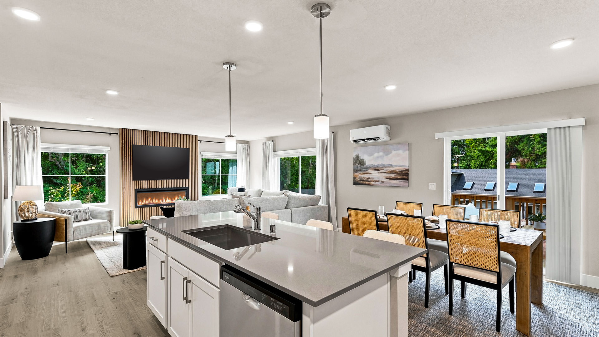 Open-concept kitchen, dining, and living area with a large island, fireplace, TV, and sliding glass door.