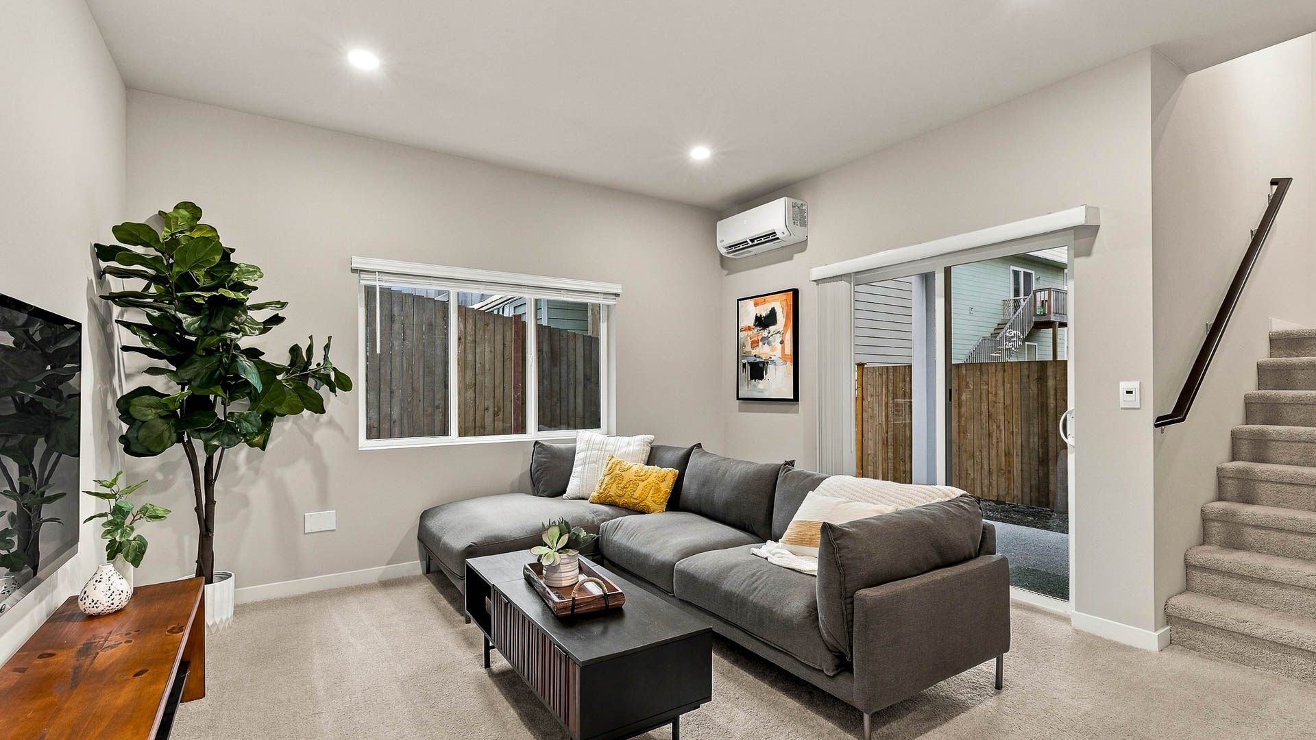 Modern kitchen with white shaker cabinets, quartz countertops, stainless steel appliances, a large center island with three stools, and sliding glass doors.
