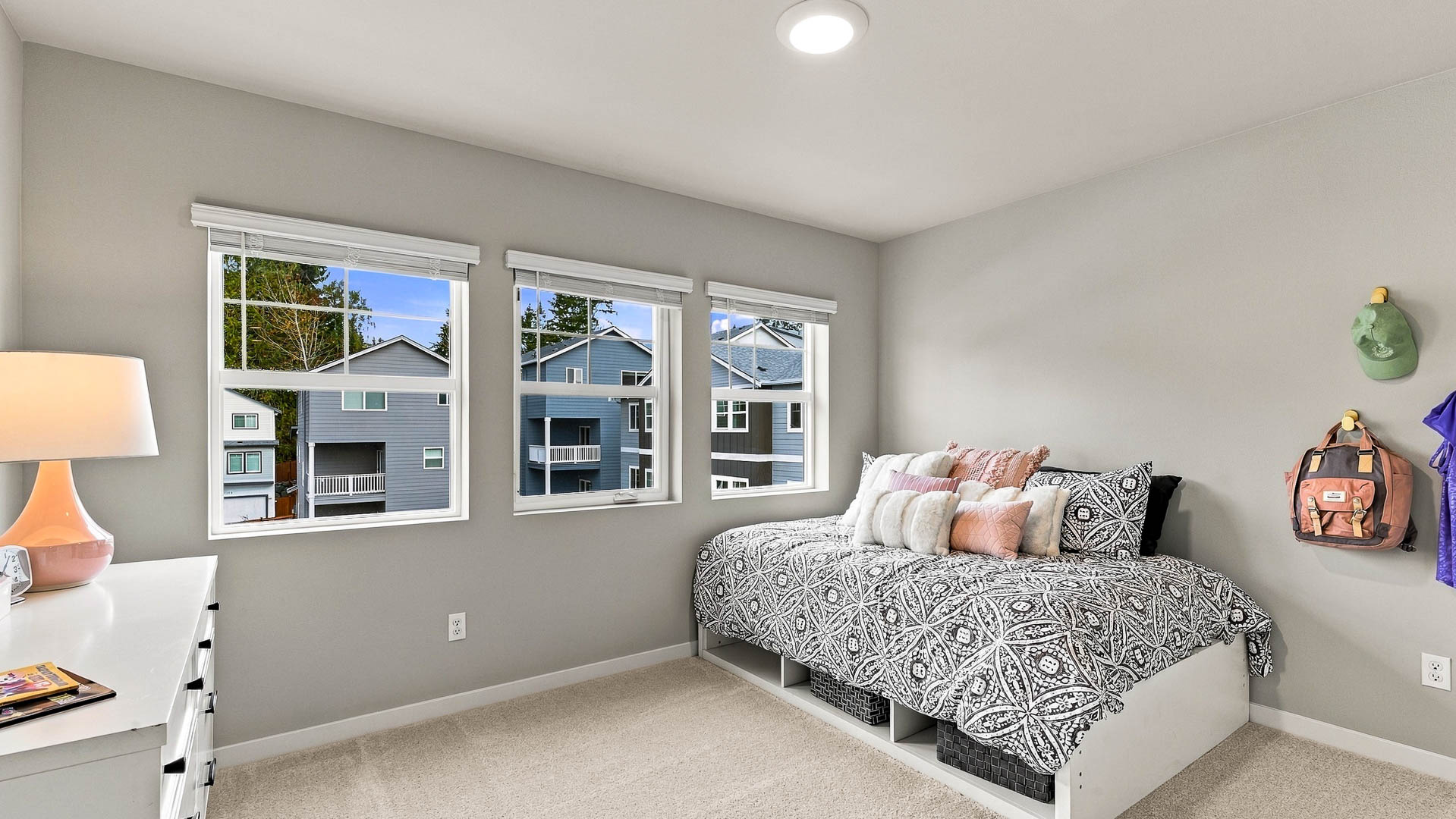 Open dining area leading into a modern white kitchen with a center island, stainless steel appliances, wood-look flooring, and recessed lighting.