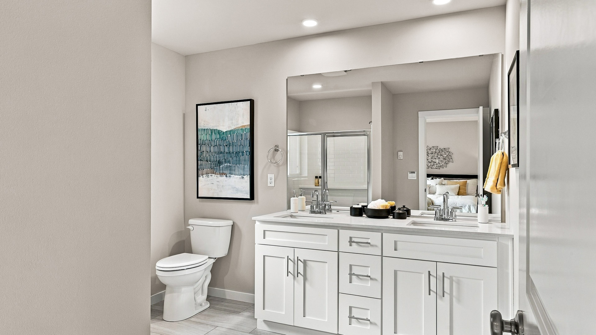 Bathroom with white vanity and large mirror, toilet, white subway-tile tub and shower surround, pink towels, plants, and framed giraffe artwork.