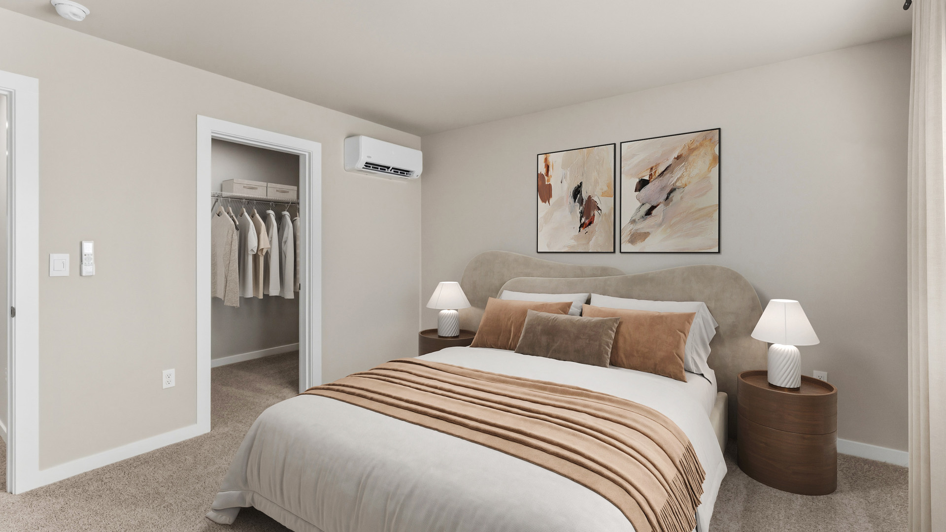 Bedroom facing an upholstered bed with white bedding and a tan throw, matching round nightstands and lamps, abstract artwork, open closet, and wall-mounted air conditioner.