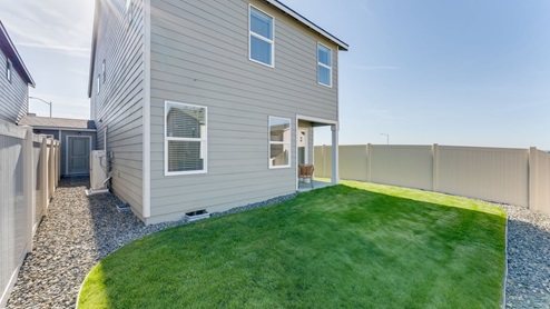backyard with sod and vinyl plank fence and covered patio