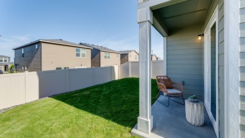 backyard with sod and vinyl plank fence and covered patio