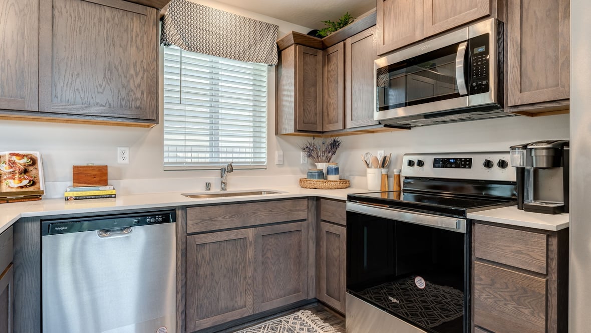 U-shaped kitchen with shaker cabinets, quartz counters, stainless steel appliances, pantry, and a breakfast bar