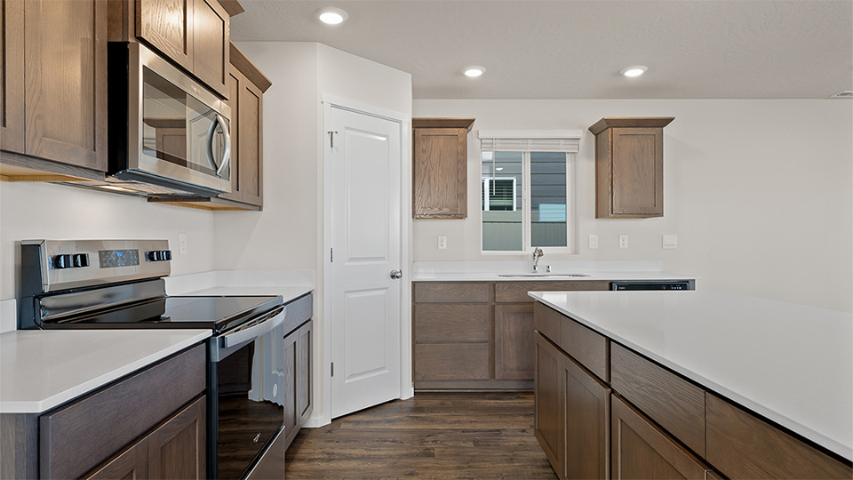 Kitchen with shaker cabinets, quartz counters, stainless steel appliances, pantry, and an island with a breakfast bar