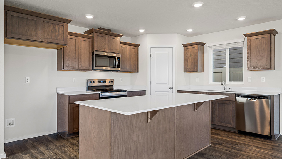 Kitchen with shaker cabinets, quartz counters, stainless steel appliances, pantry, and an island with a breakfast bar