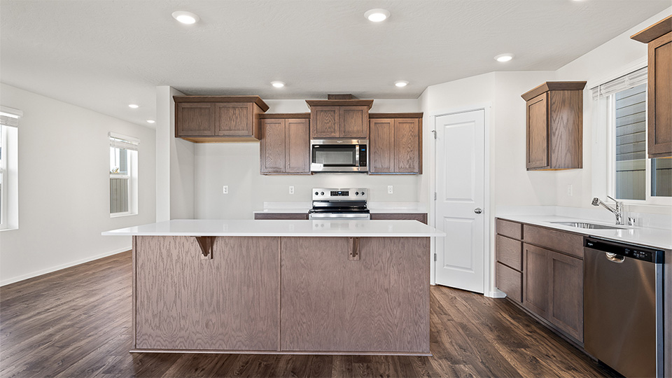 Kitchen with shaker cabinets, quartz counters, stainless steel appliances, pantry, and an island with a breakfast bar