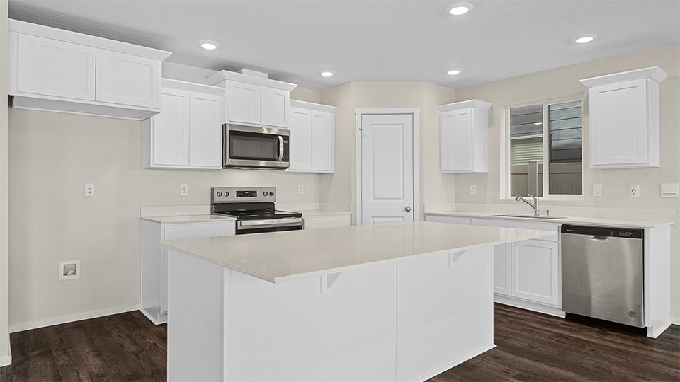 Kitchen with shaker cabinets, quartz counters, stainless steel appliances, pantry, and an island with a breakfast bar