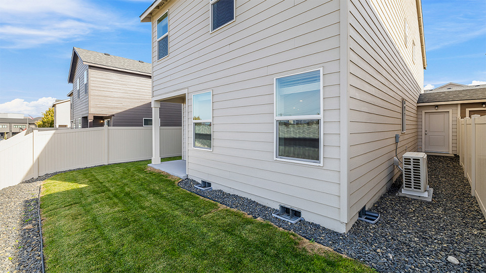 fenced backyard with sod lawn and a covered patio