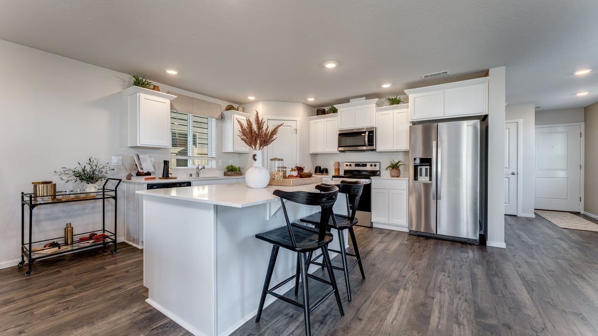 Kitchen with shaker cabinets, quartz counters, stainless steel appliances, pantry, and an island with a breakfast bar