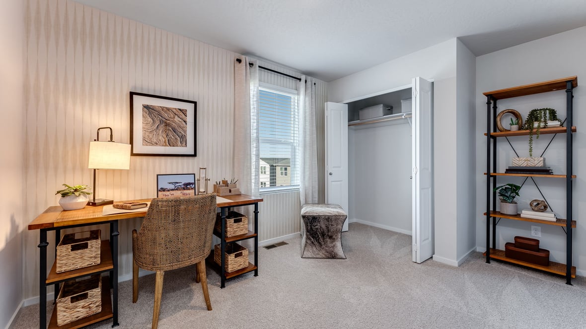 A guest bedroom with wall-to-wall carpet, window and a full-sized bed