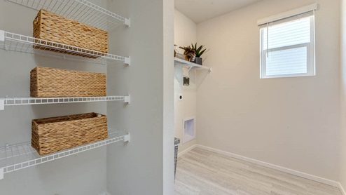 laundry room with white wire shelves and a window, and premium laminate flooring