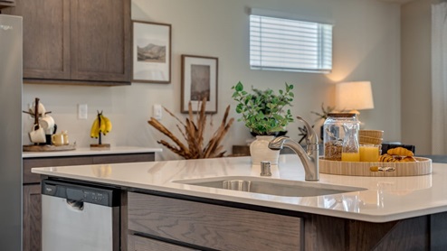Kitchen with shaker cabinets, quartz counters, stainless steel appliances, pantry, and an island with a breakfast bar