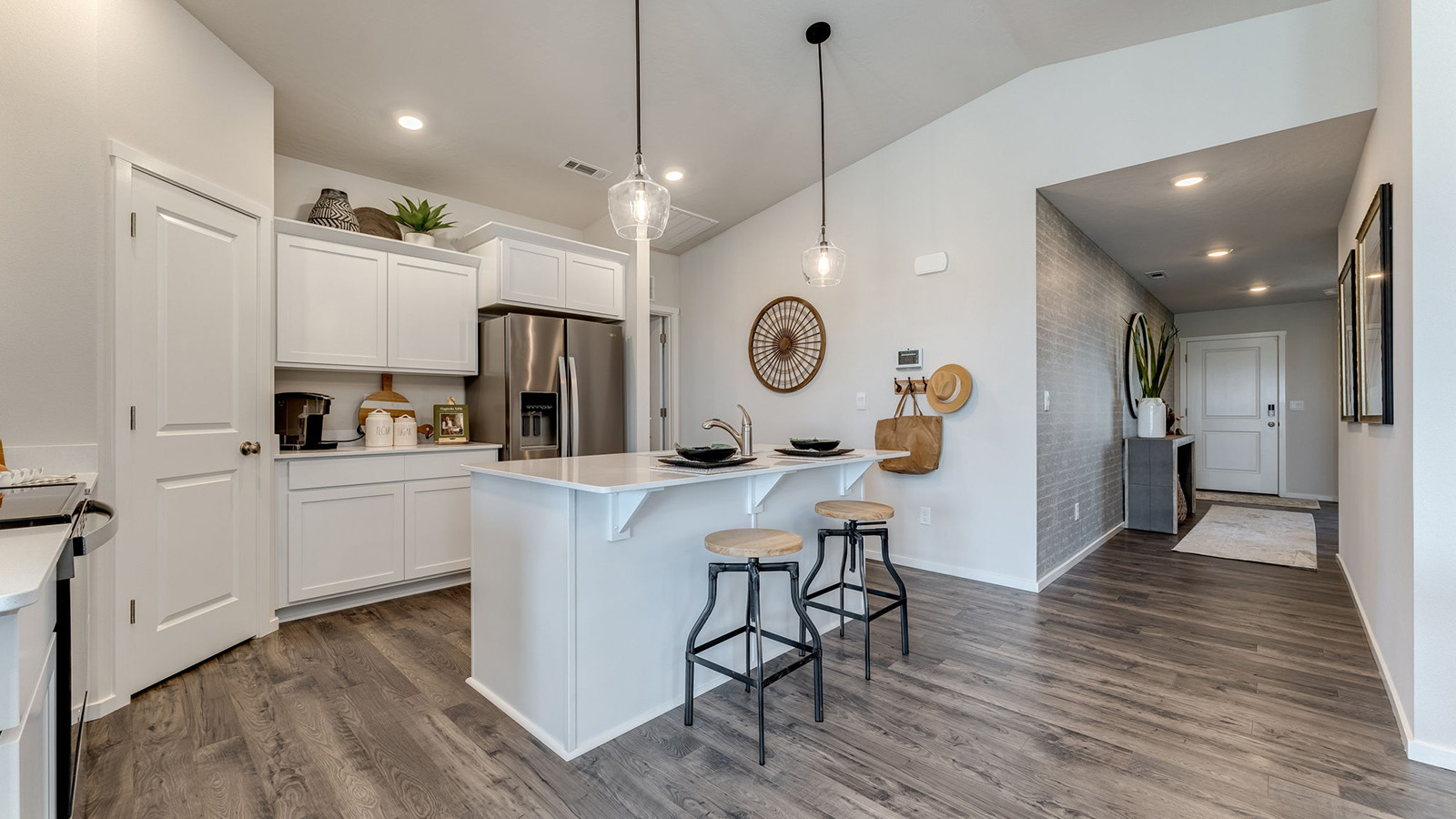 Kitchen with shaker cabinets, quartz counters, stainless steel appliances, pantry, and an island with a breakfast bar