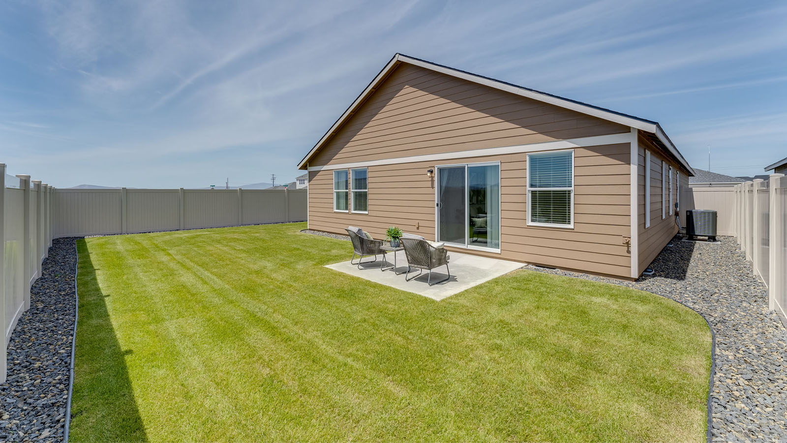 fully fenced backyard with sod lawn and a patio