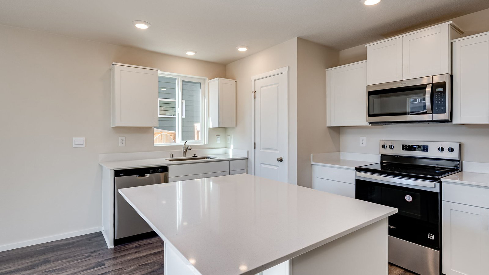 Kitchen with shaker cabinets, quartz counters, stainless steel appliances, pantry, and an island with a breakfast bar
