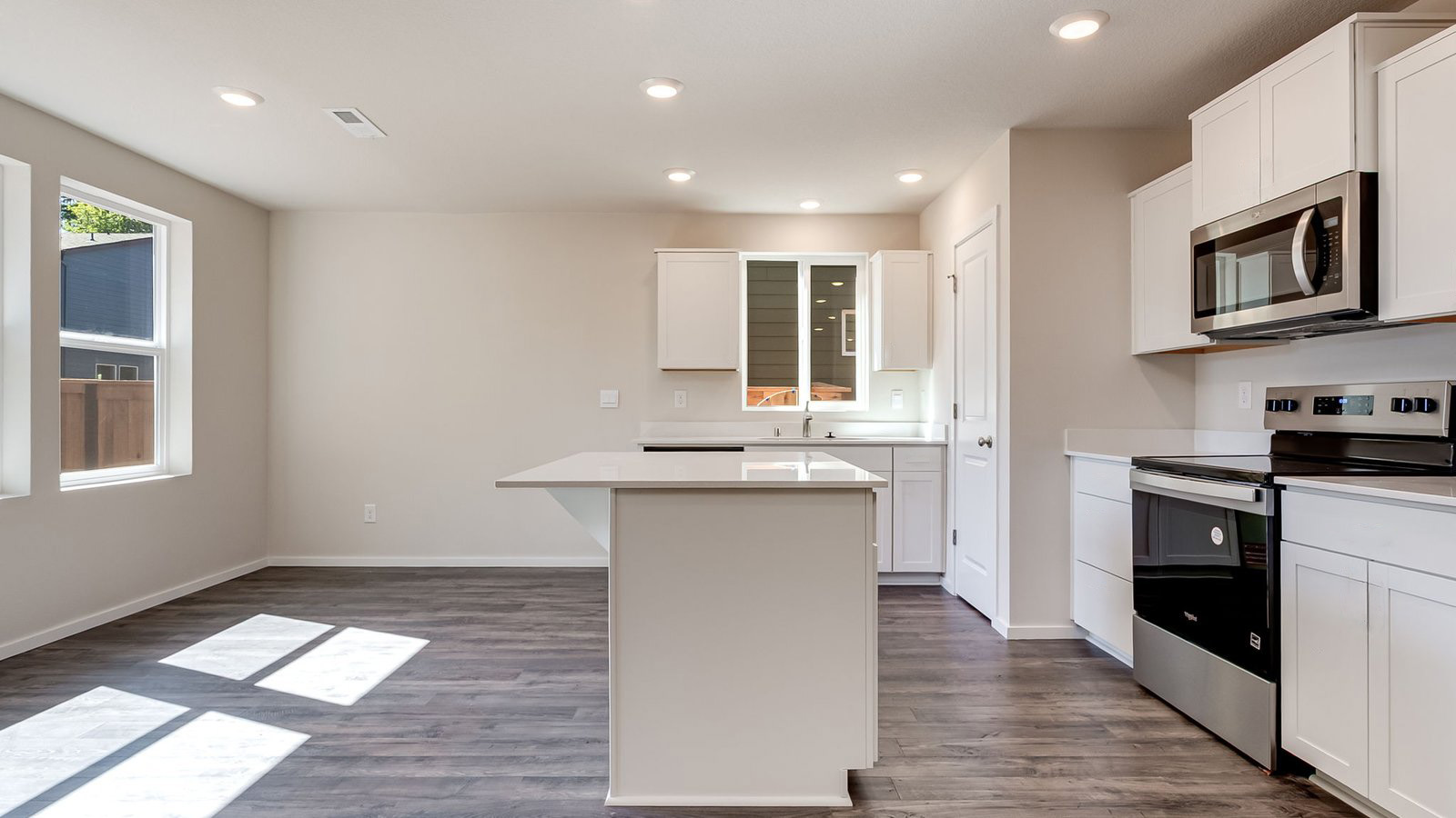 Kitchen with shaker cabinets, quartz counters, stainless steel appliances, pantry, and an island with a breakfast bar
