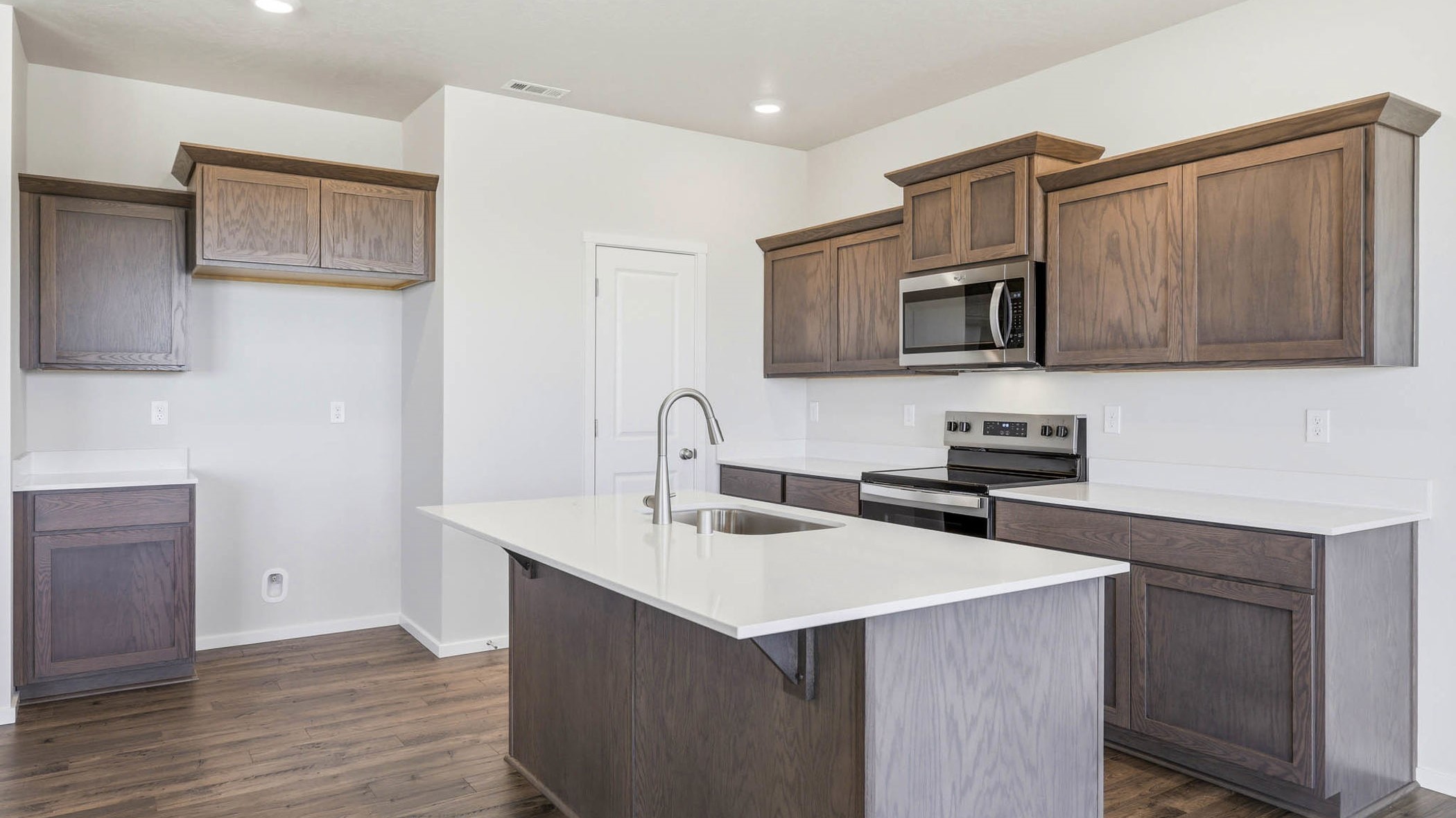 Kitchen with shaker cabinets, quartz counters, stainless steel appliances, pantry, and an island with a breakfast bar
