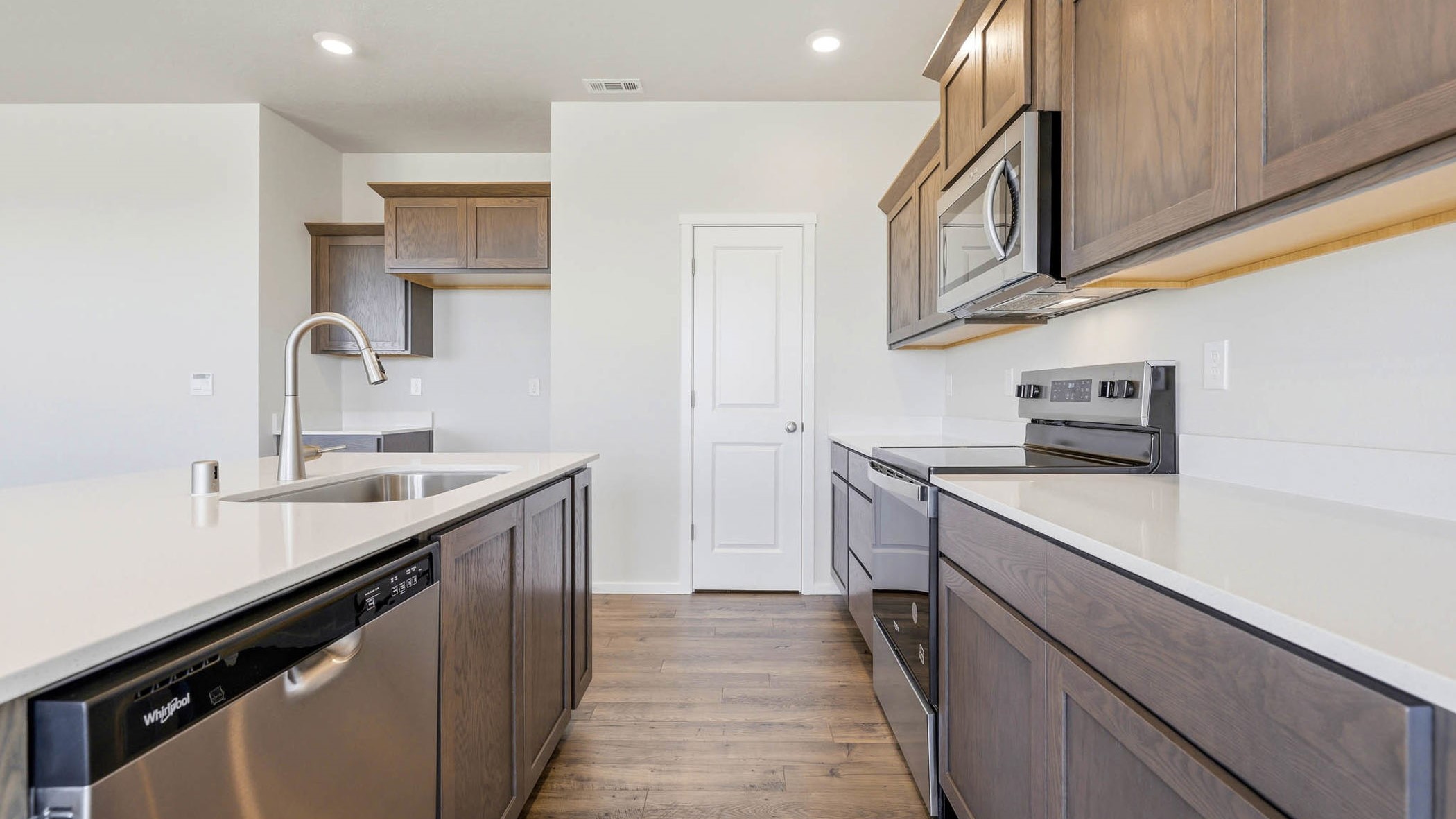Kitchen with shaker cabinets, quartz counters, stainless steel appliances, pantry, and an island with a breakfast bar