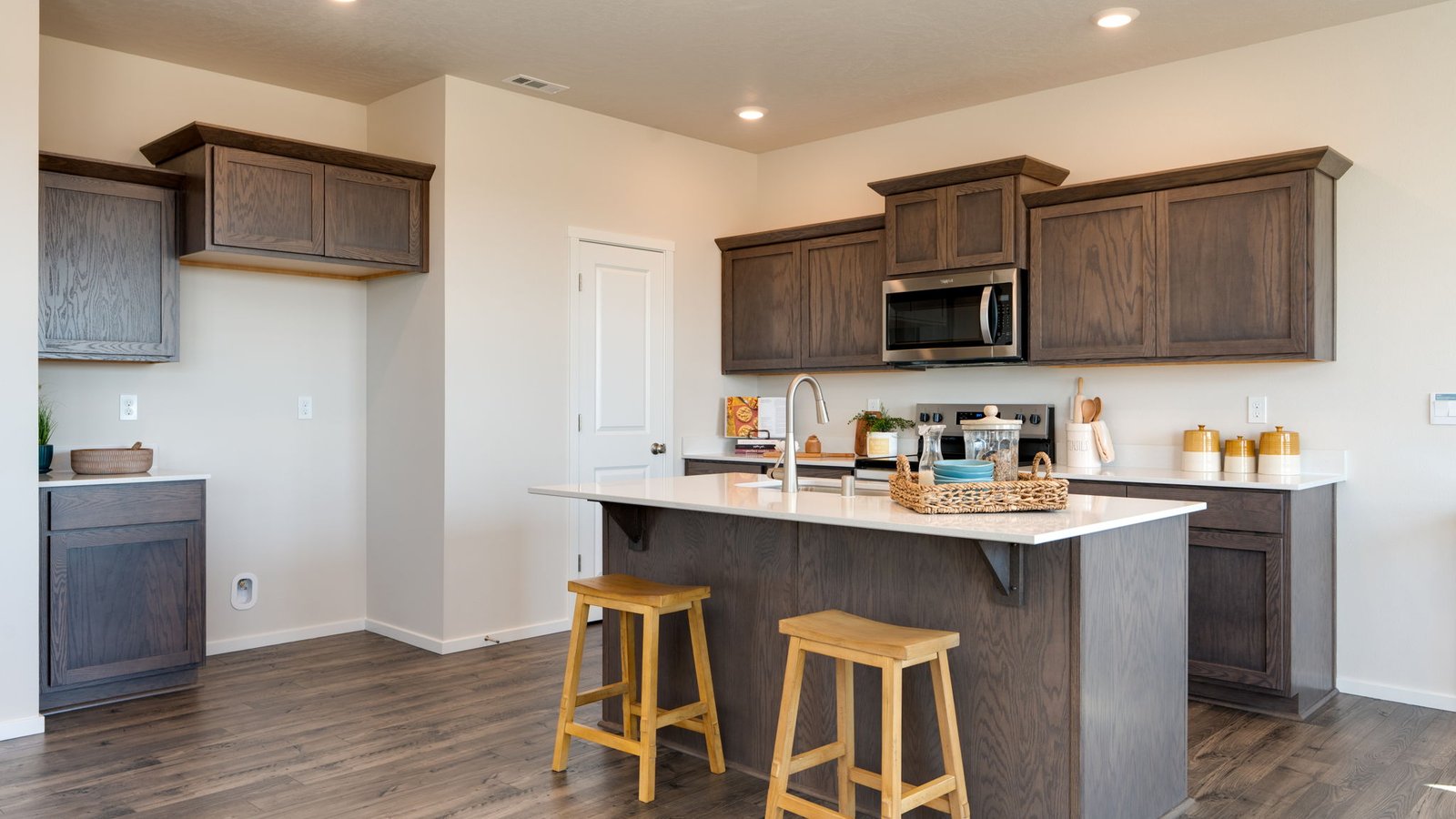 Kitchen with shaker cabinets, quartz counters, stainless steel appliances, pantry, and an island with a breakfast bar