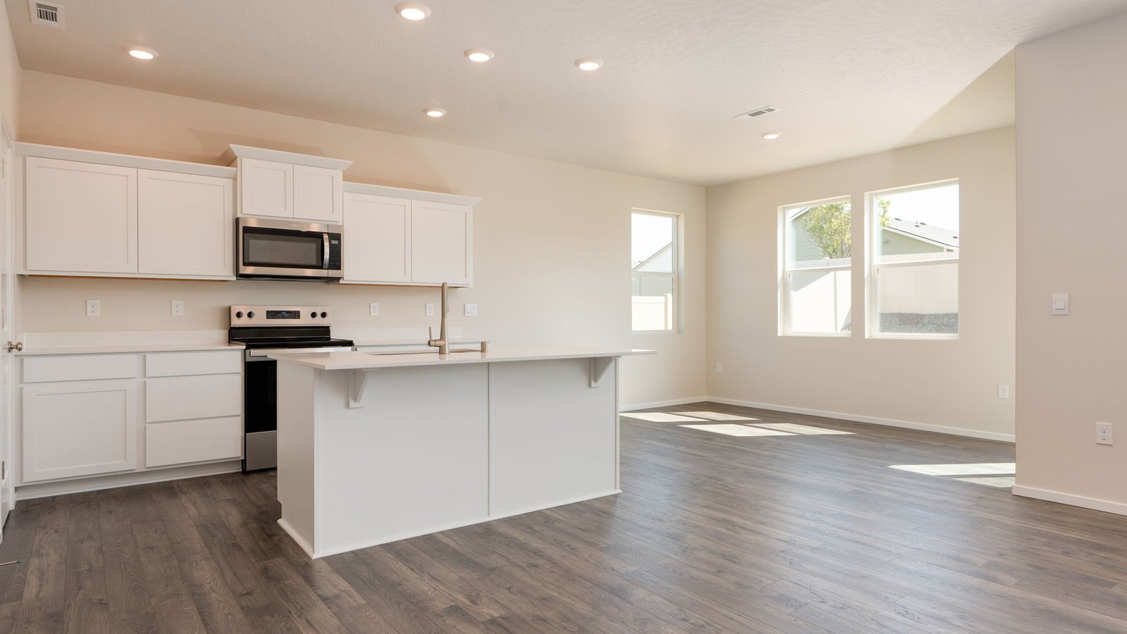 Kitchen with shaker cabinets, quartz counters, stainless steel appliances, pantry, and an island with a breakfast bar