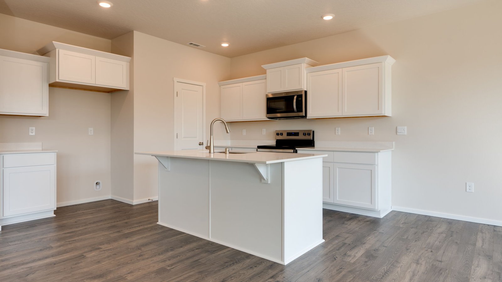 Kitchen with shaker cabinets, quartz counters, stainless steel appliances, pantry, and an island with a breakfast bar