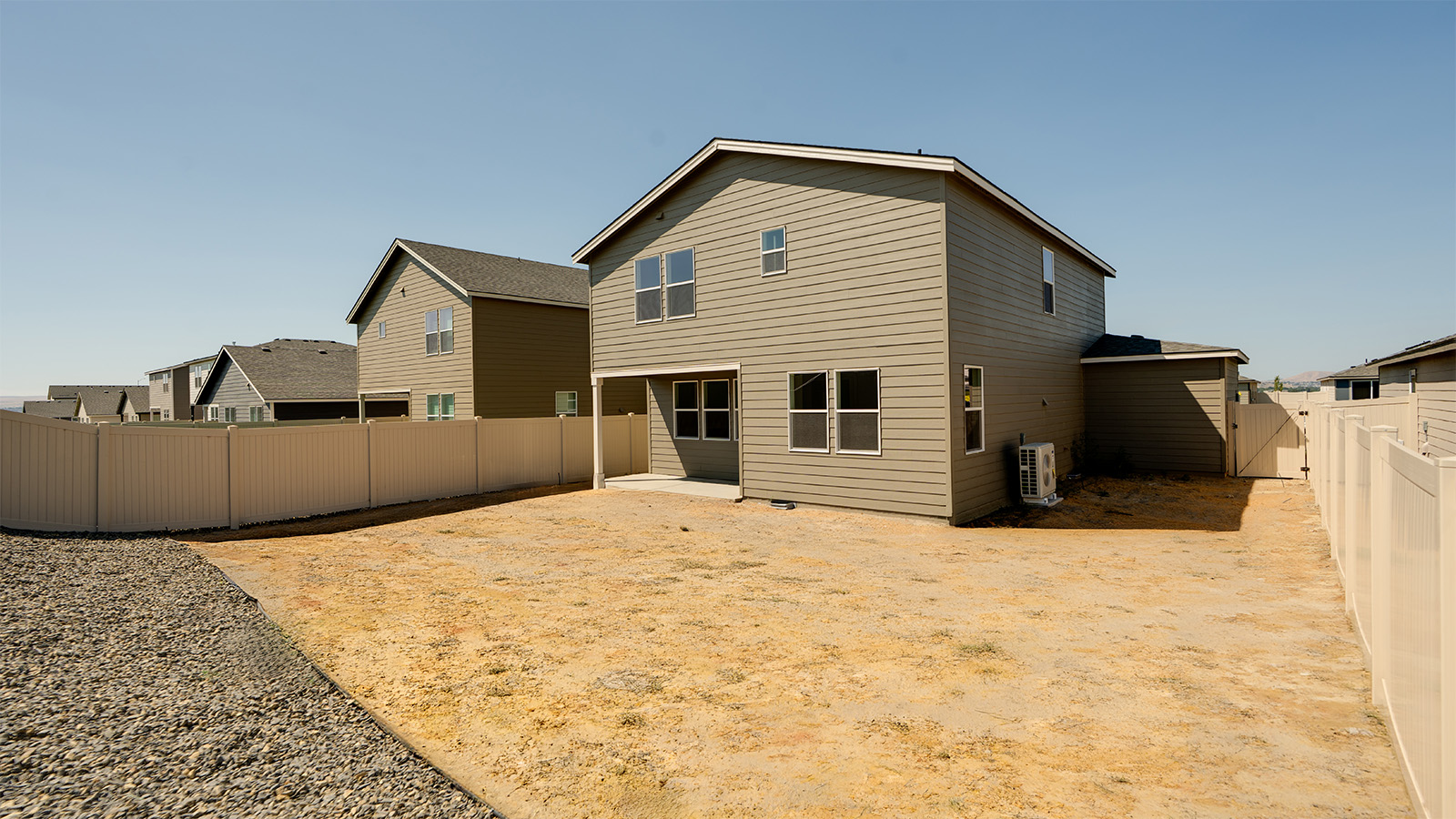 fully fenced backyard with bark chips and a patio