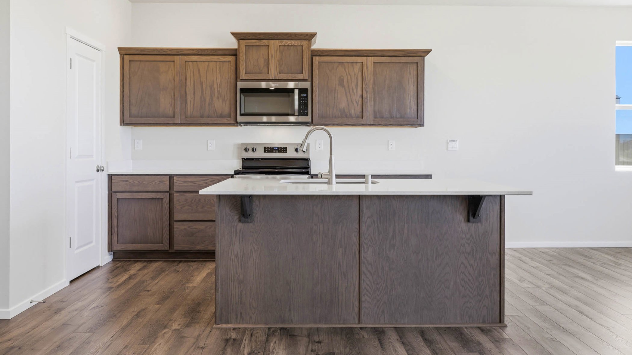 Kitchen with shaker cabinets, quartz counters, stainless steel appliances, pantry, and an island with a breakfast bar