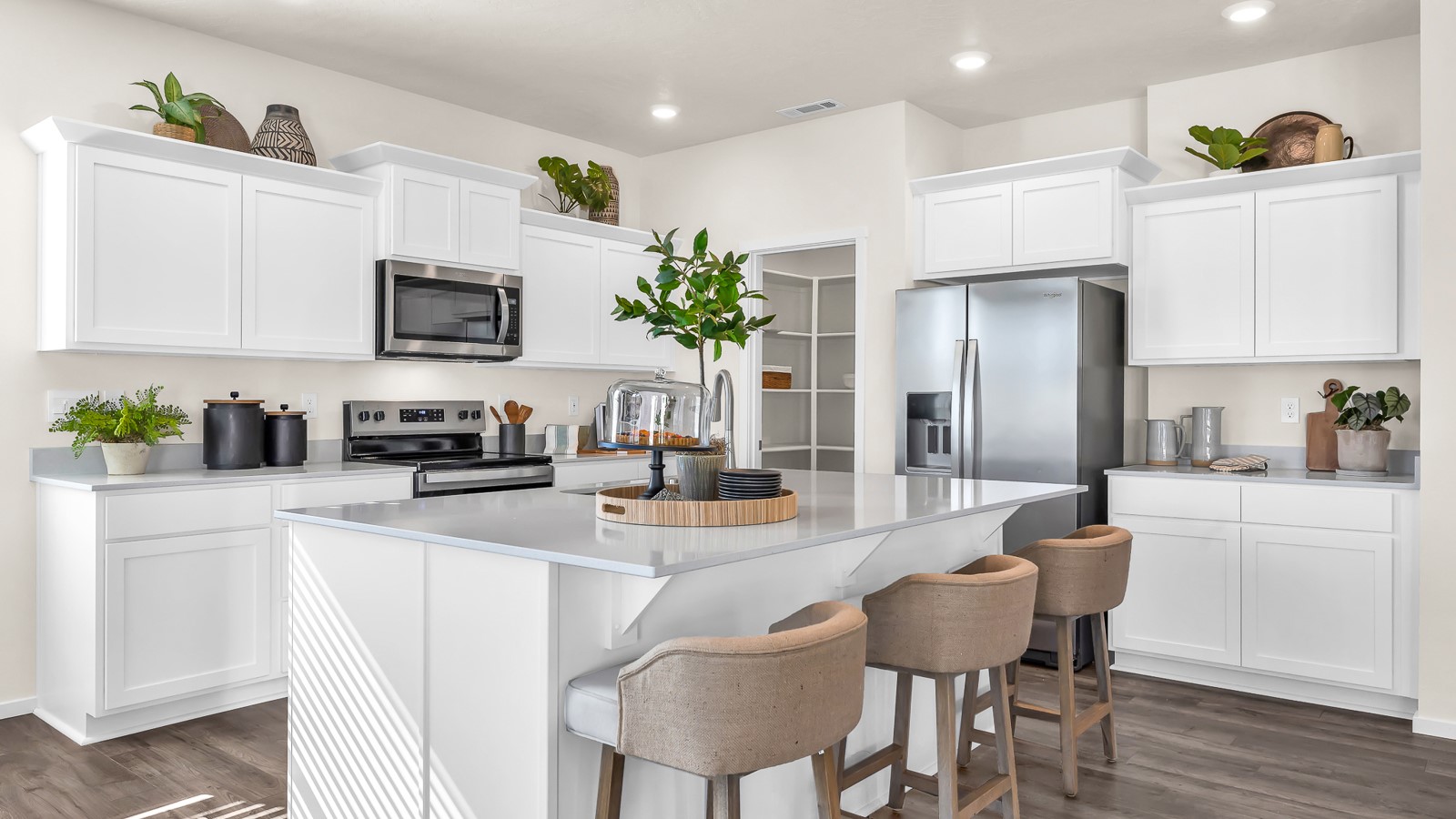 Kitchen with shaker cabinets, quartz counters, stainless steel appliances, pantry, and an island with a breakfast bar