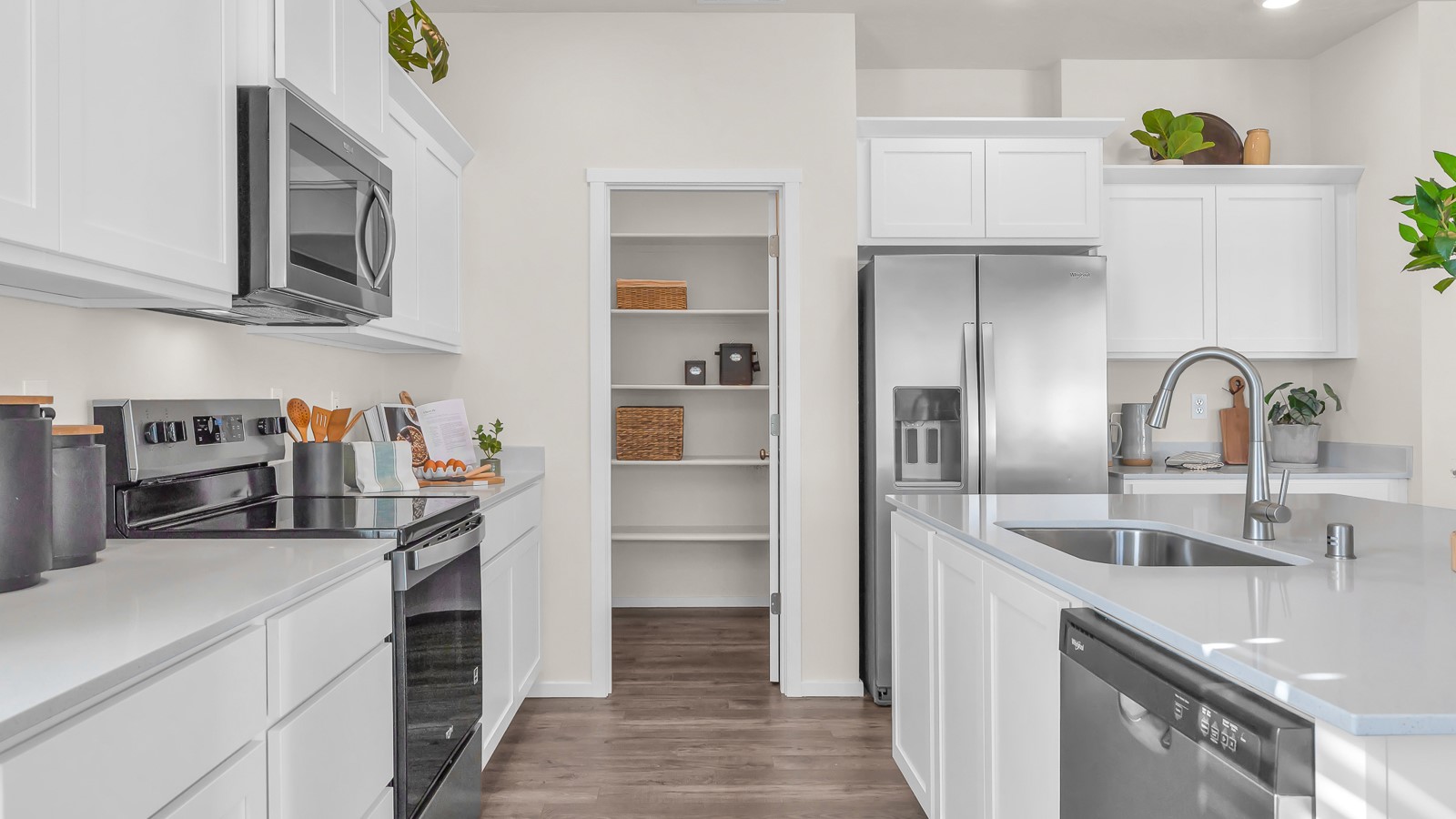 Kitchen with shaker cabinets, quartz counters, stainless steel appliances, pantry, and an island with a breakfast bar