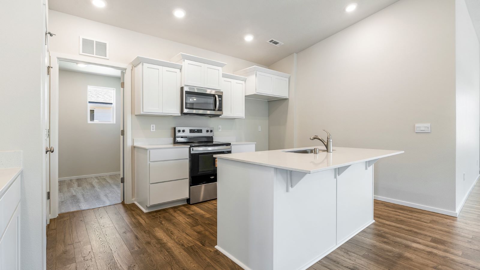 Kitchen with shaker cabinets, quartz counters, stainless steel appliances, pantry, and an island with a breakfast bar