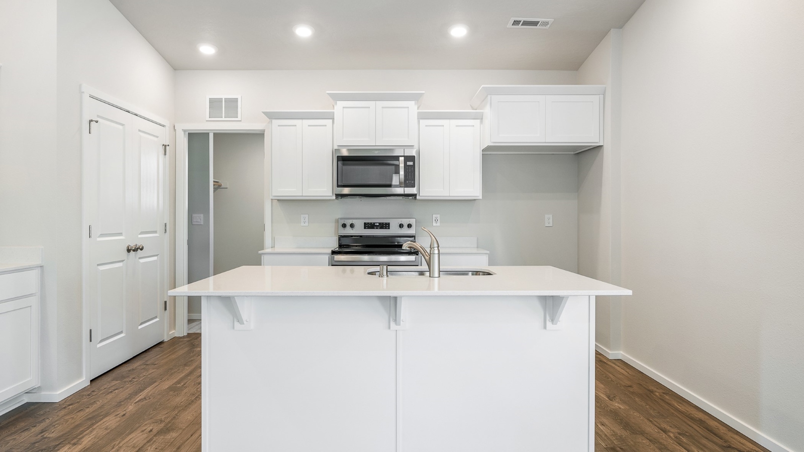 Kitchen with shaker cabinets, quartz counters, stainless steel appliances, pantry, and an island with a breakfast bar