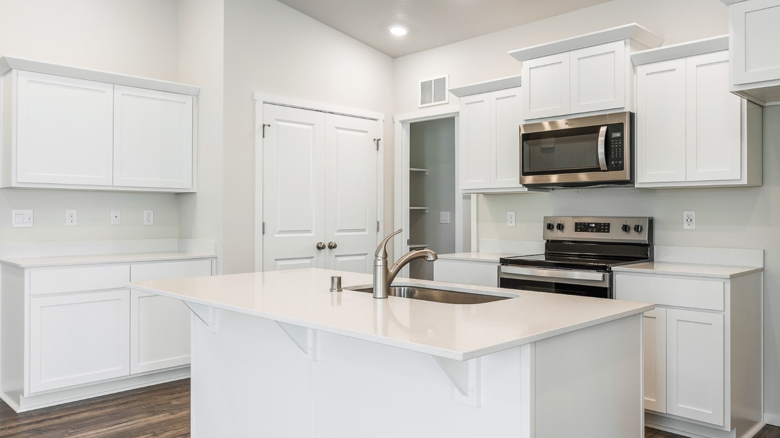 Kitchen with shaker cabinets, quartz counters, stainless steel appliances, pantry, and an island with a breakfast bar