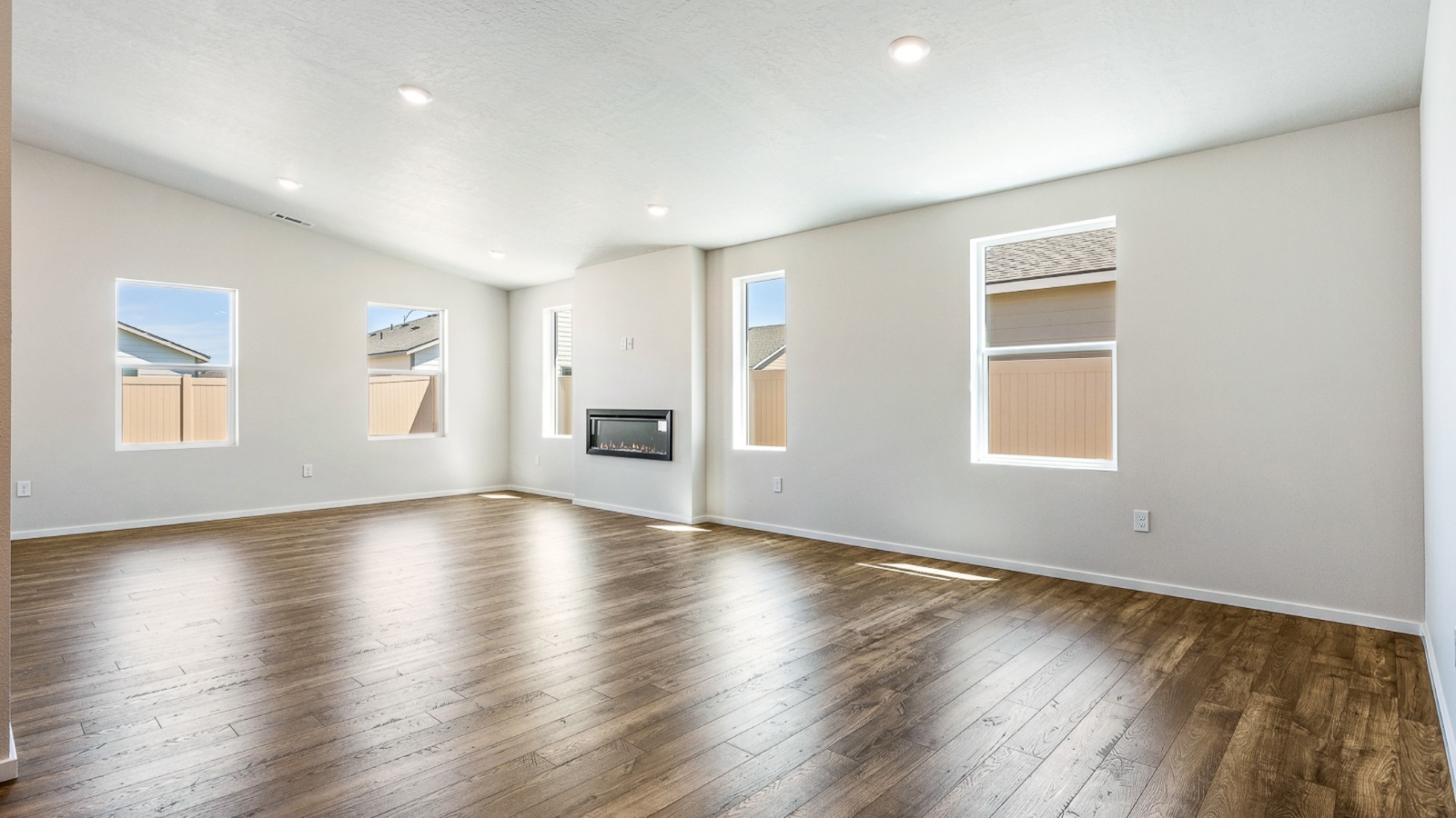 Great room with laminate flooring and an electric fireplace and vaulted ceilings