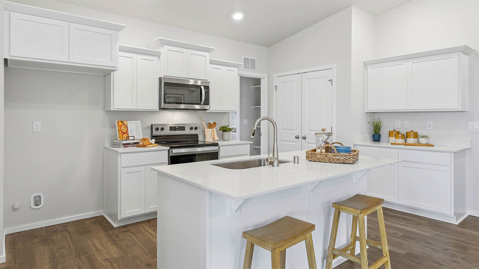 Kitchen with shaker cabinets, quartz counters, stainless steel appliances, pantry, and an island with a breakfast bar