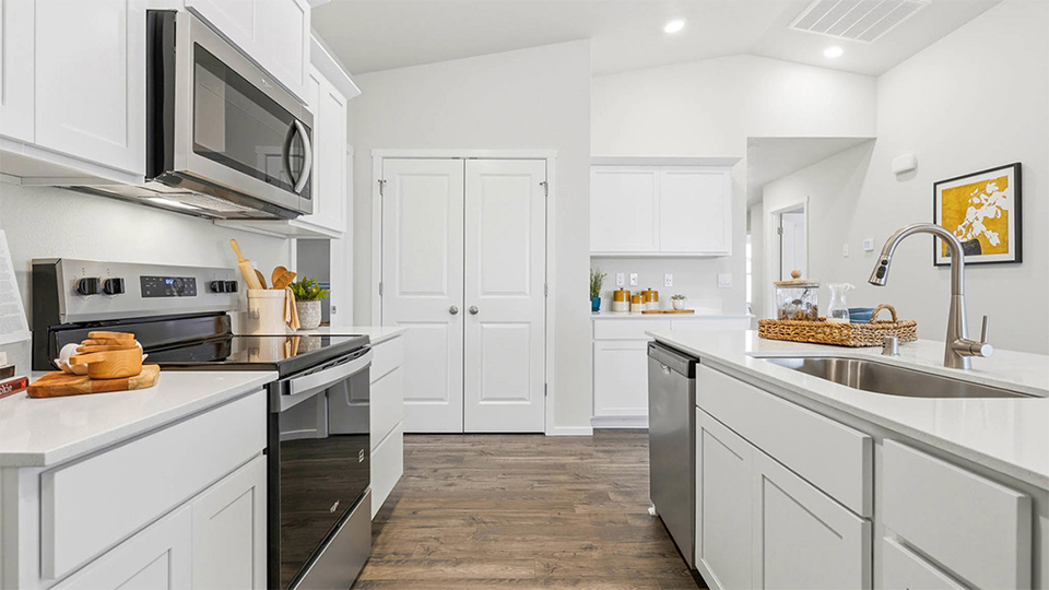 Kitchen with shaker cabinets, quartz counters, stainless steel appliances, pantry, and an island with a breakfast bar