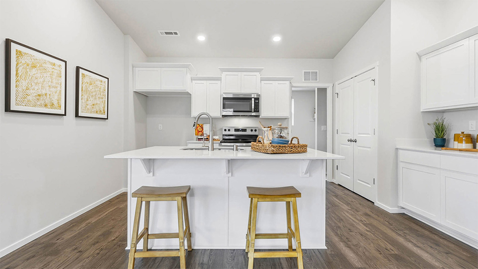 Kitchen with shaker cabinets, quartz counters, stainless steel appliances, pantry, and an island with a breakfast bar