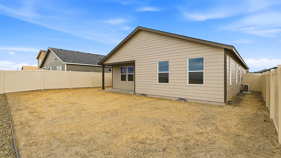 fully fenced backyard with bark chips and a patio
