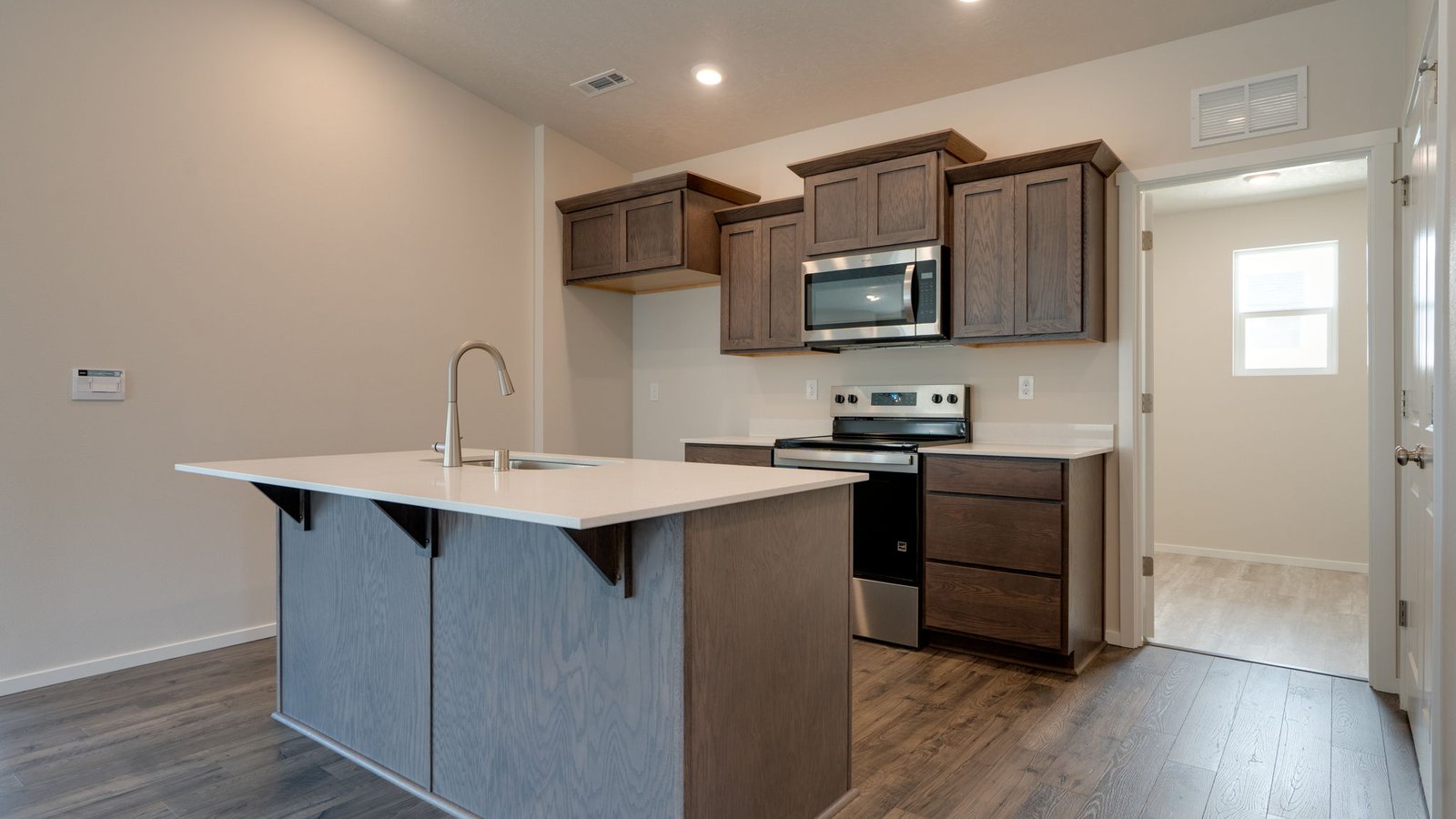 Kitchen with shaker cabinets, quartz counters, stainless steel appliances, pantry, and an island with a breakfast bar