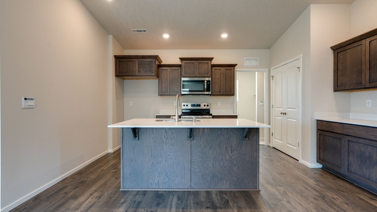 Kitchen with shaker cabinets, quartz counters, stainless steel appliances, pantry, and an island with a breakfast bar