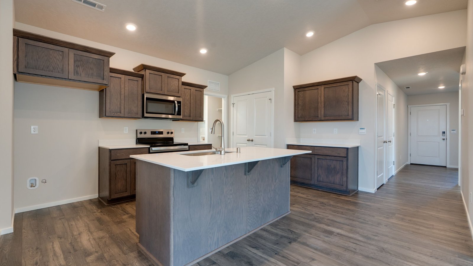 Kitchen with shaker cabinets, quartz counters, stainless steel appliances, pantry, and an island with a breakfast bar