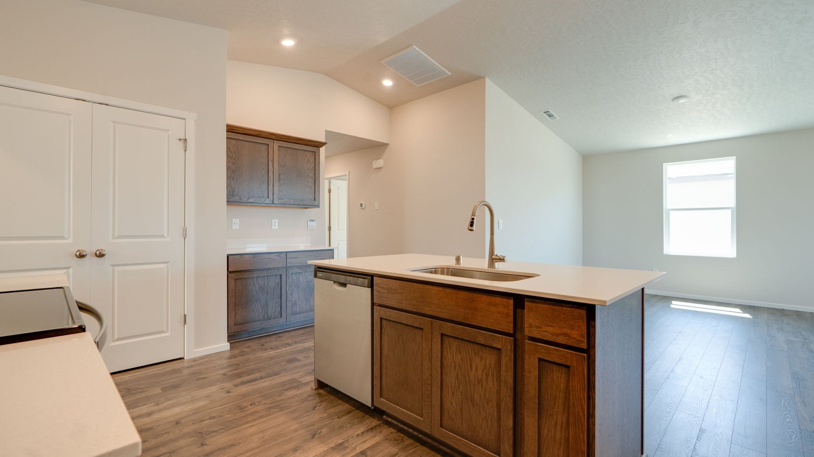 Kitchen with shaker cabinets, quartz counters, stainless steel appliances, pantry, and an island with a breakfast bar