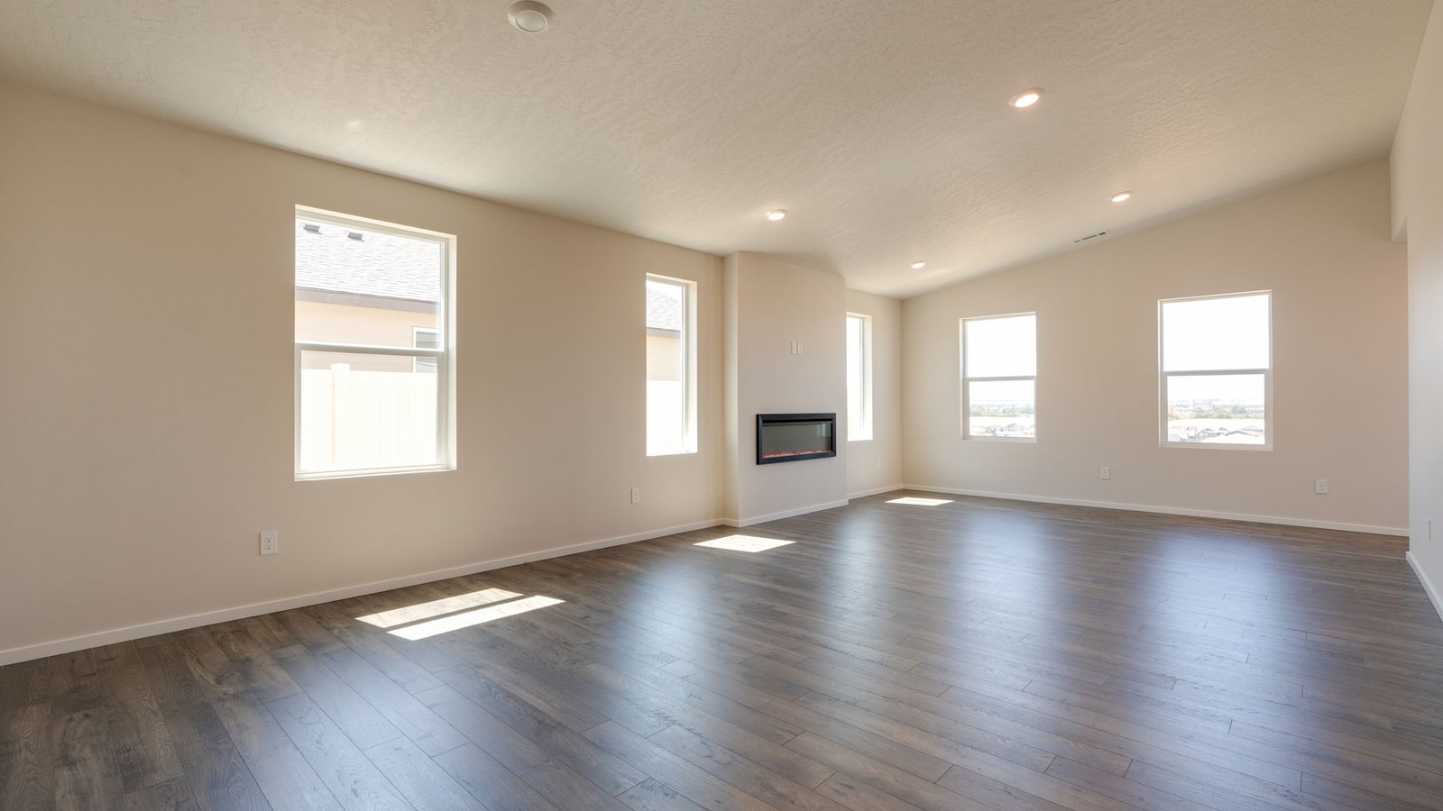 Great room with laminate flooring and an electric fireplace and vaulted ceilings