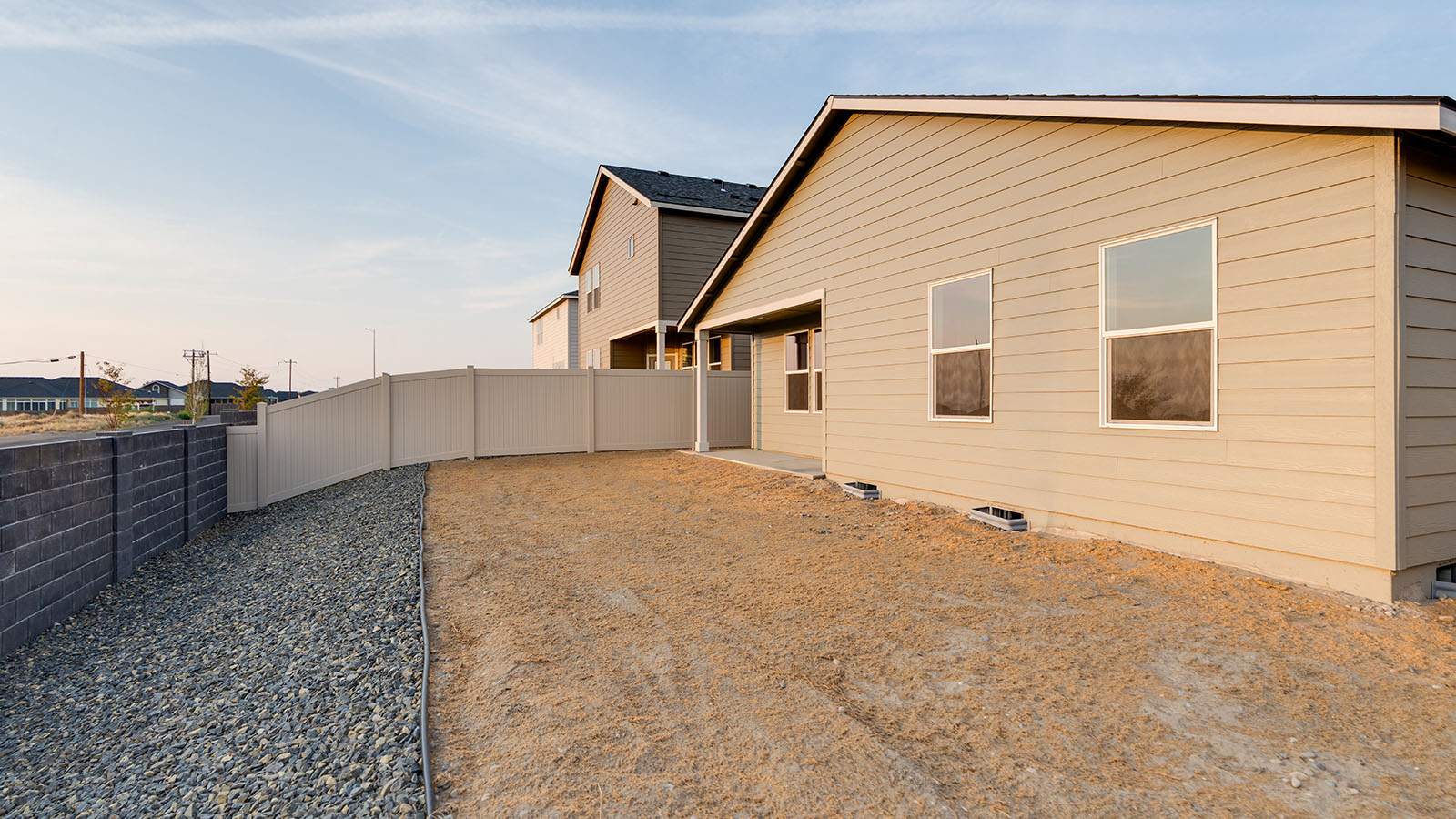 fully fenced backyard with bark chips and a patio