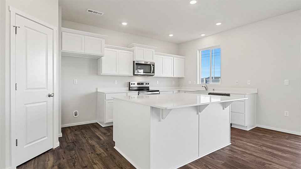 Kitchen with shaker cabinets, quartz counters, stainless steel appliances, pantry, and an island with a breakfast bar